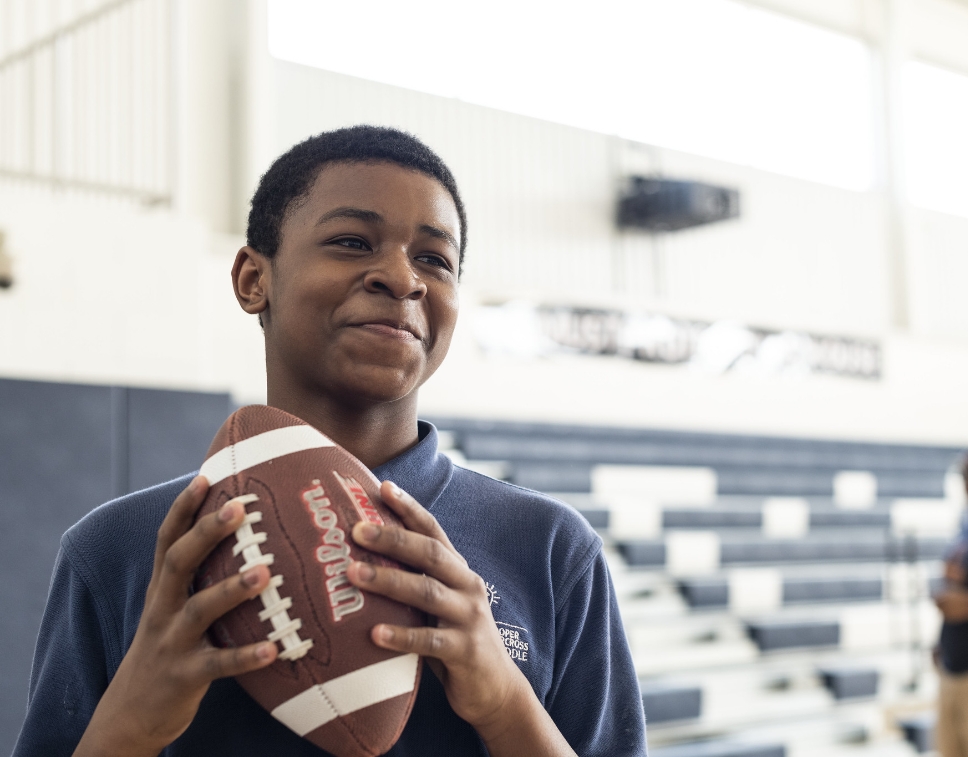 student in a gym holding a football
