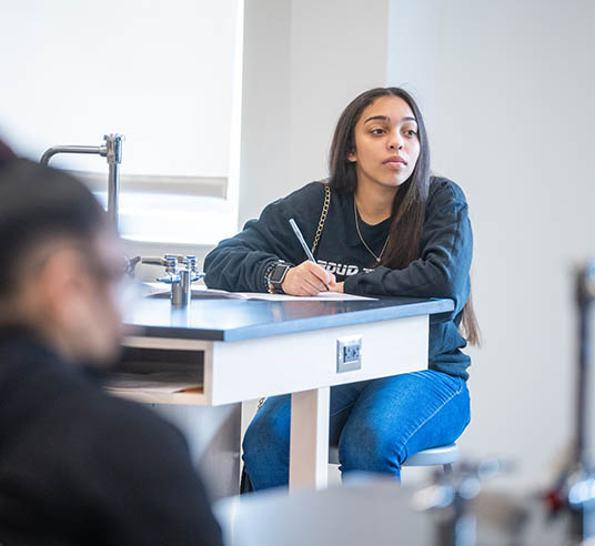 student in classroom writing and listening