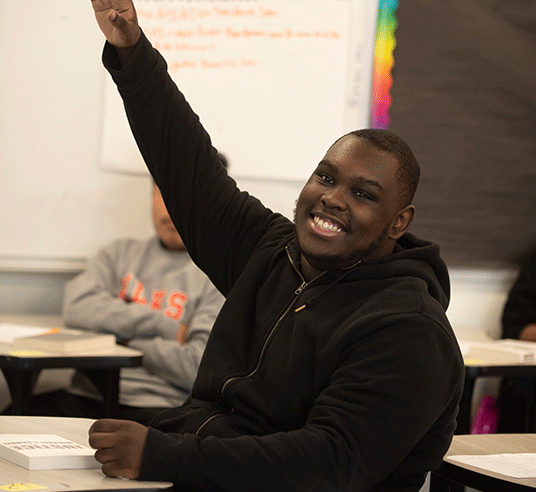 high school student smiling with hand raised