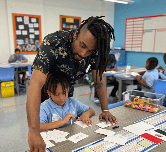 teacher assisting young student on classwork