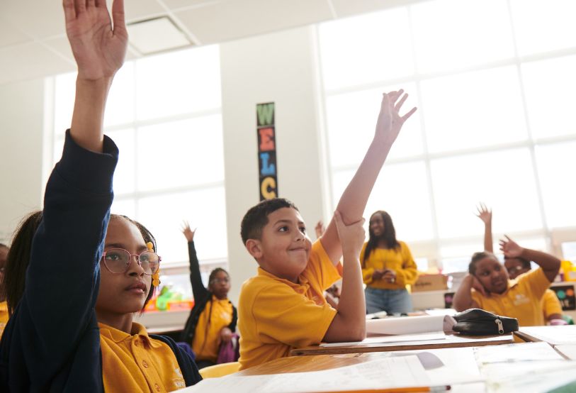 students with hands raised on classroom